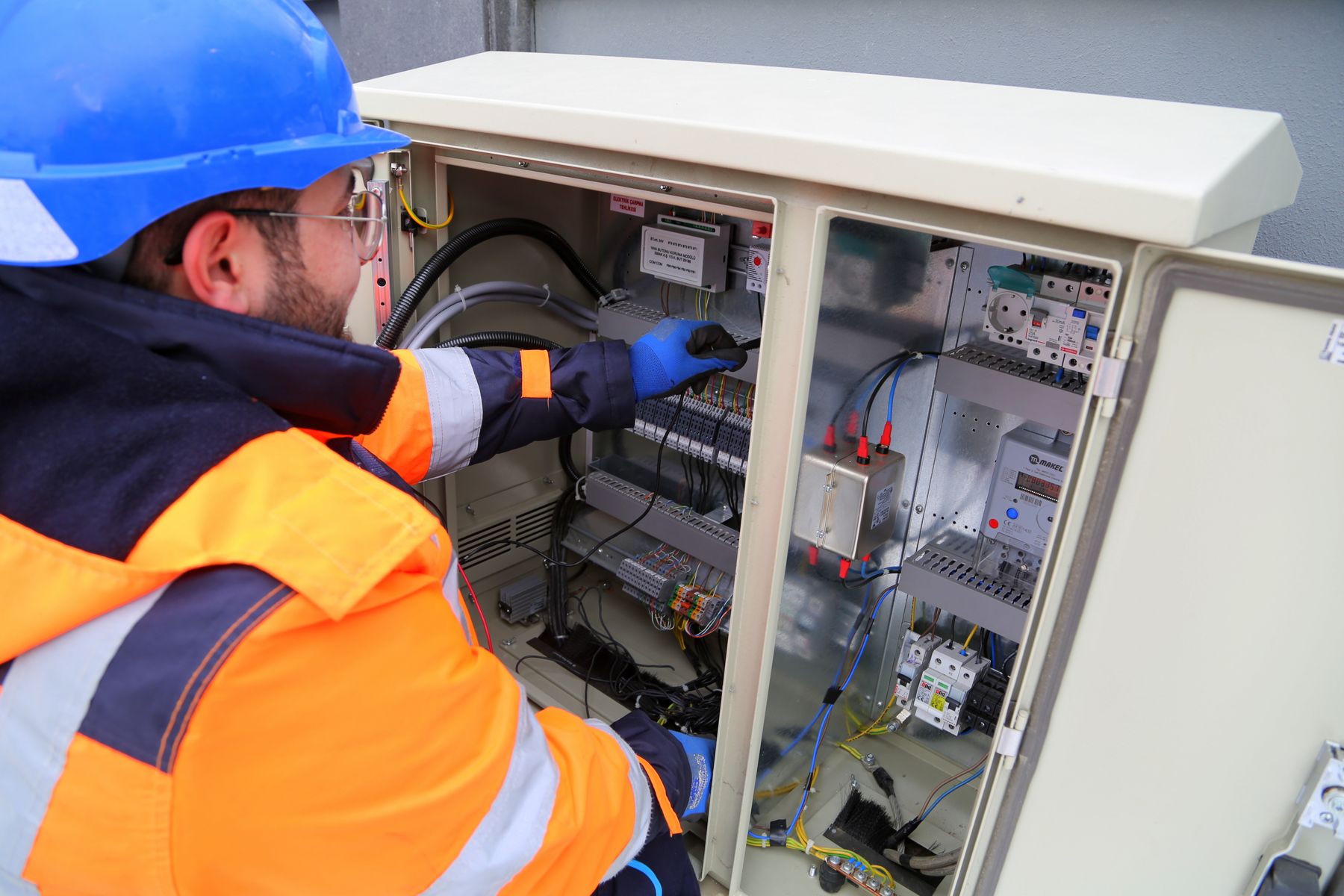 Electrician in safety gear working at an electrical panel